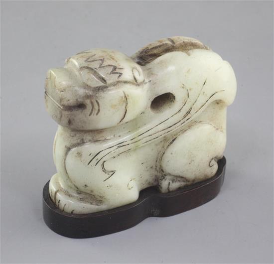 A Chinese pale celadon and black jade recumbent figure of a winged mythical beast, length 7cm, wood stand, some black staining to the s